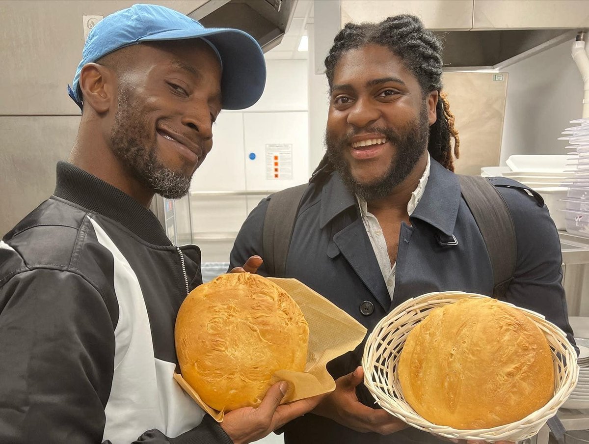 Two members beaming, holding fresh-baked bread at brunch